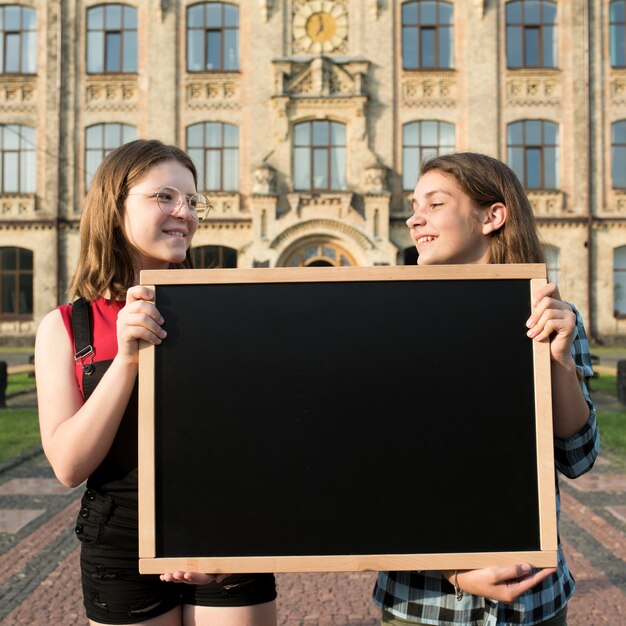 Medium shot highschool girls holding blackboard