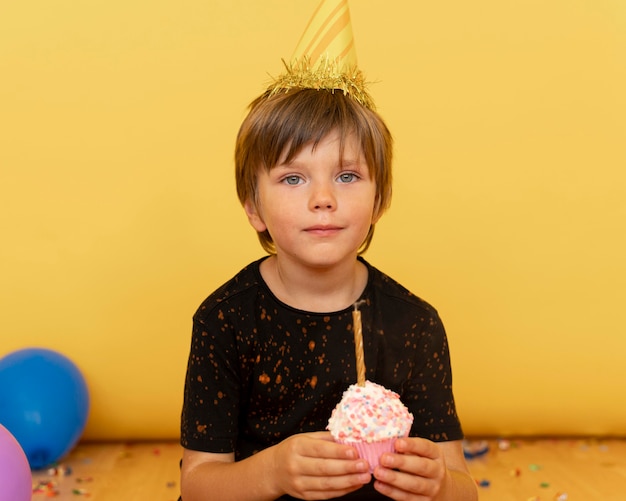 Free Photo medium shot kid holding cupcake with candle