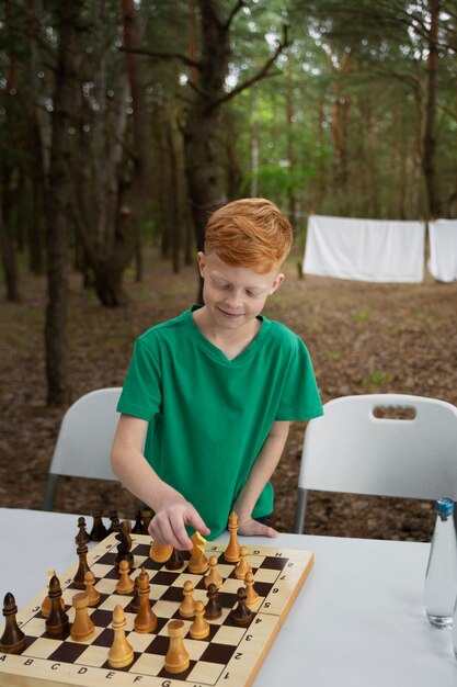 Medium shot kid playing chess outdoors