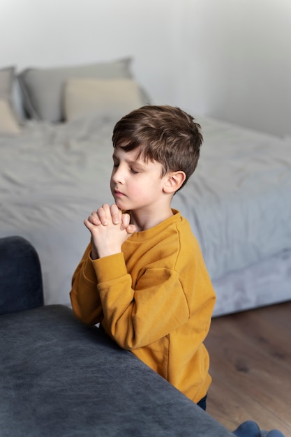 Free photo medium shot kid praying on floor