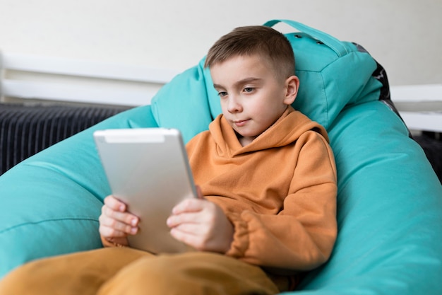 Medium shot kid studying with tablet