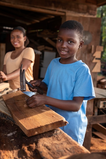 Medium shot kid with hammer hitting nail