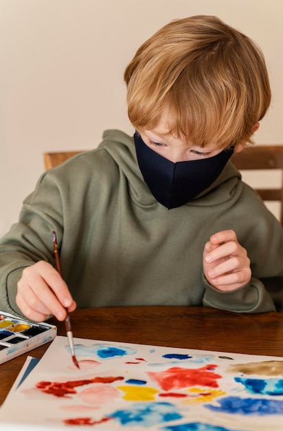 Free Photo medium shot kid with mask painting