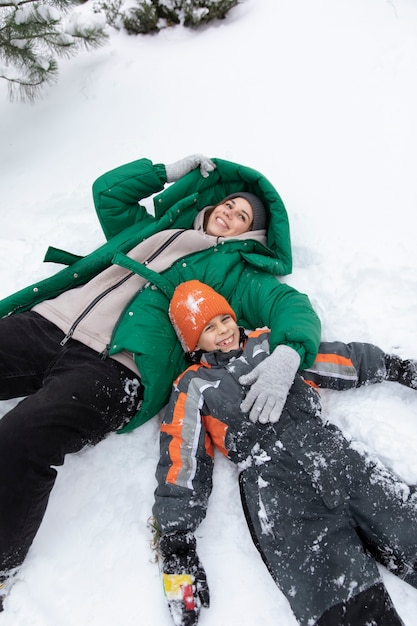 Free photo medium shot kid and woman laying in snow