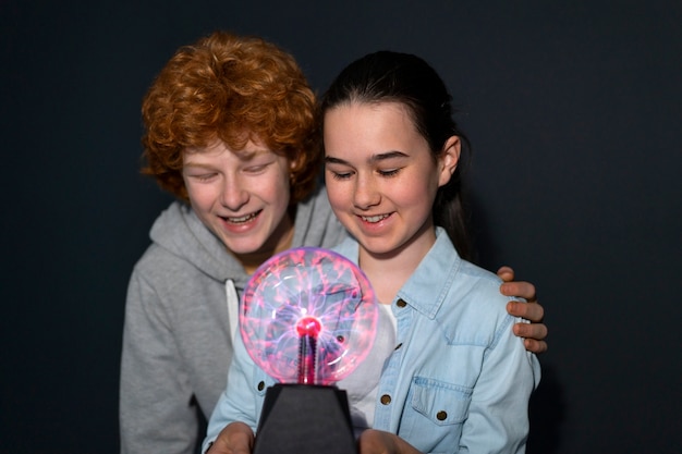 Free photo medium shot kids interacting with a plasma ball