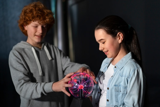 Free photo medium shot kids interacting with a plasma ball