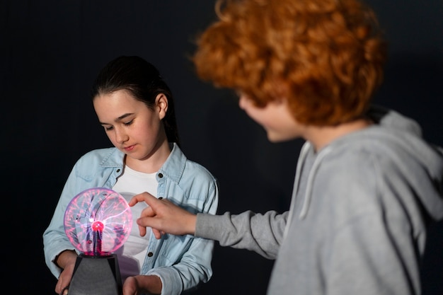 Medium shot kids interacting with a plasma ball