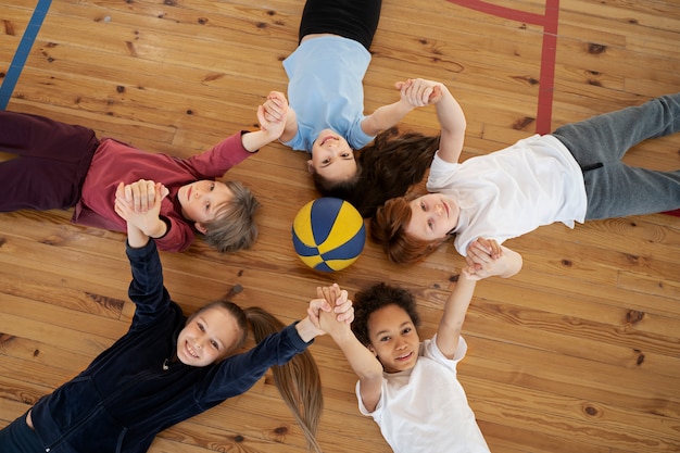 Free photo medium shot kids laying on gym floor