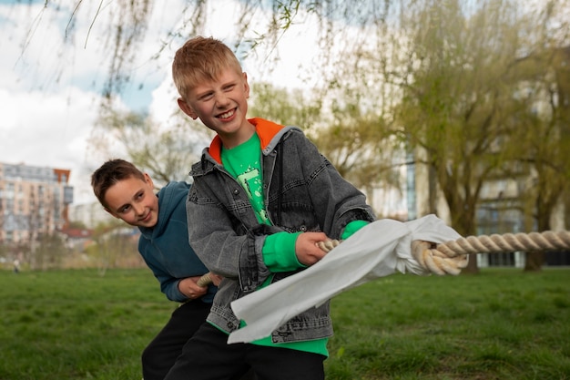 Medium shot kids playing tug-of-war in the park