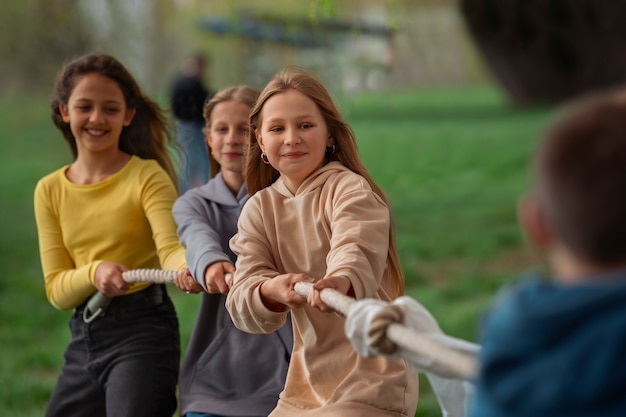 Free photo medium shot kids playing tug-of-war in the park