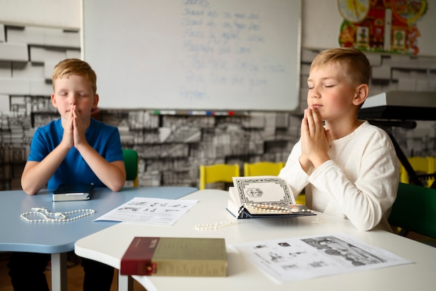 Free Photo medium shot kids praying at sunday school