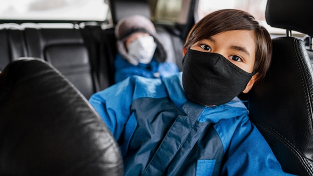 Medium shot kids wearing masks in car