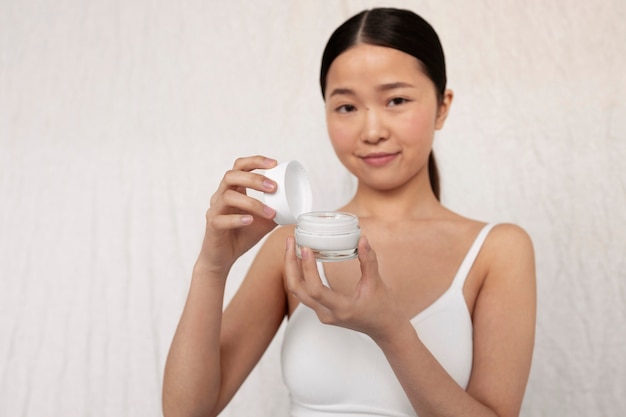 Medium shot korean woman posing with face cream