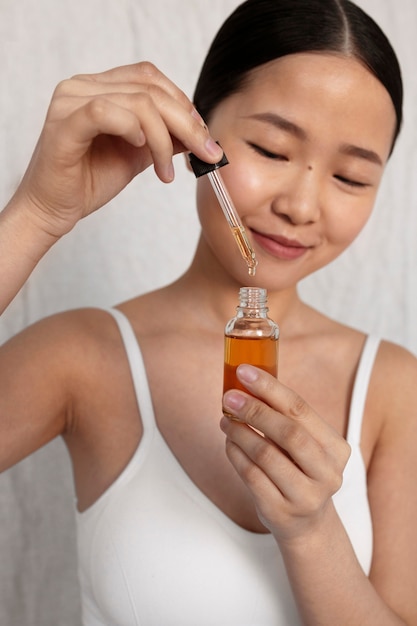 Free photo medium shot korean woman posing with serum