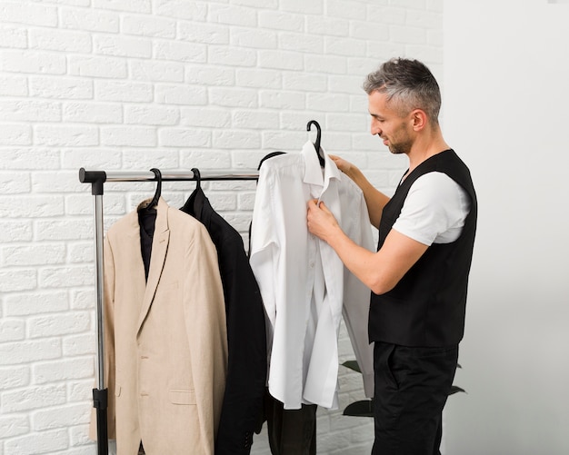 Medium shot of man arranging his shirts