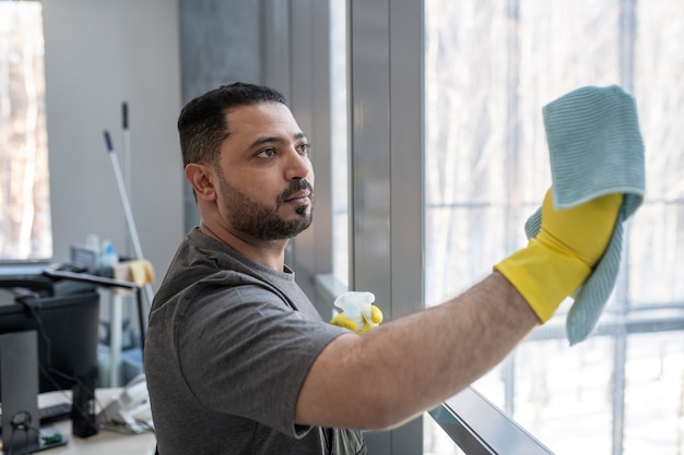 Medium shot man cleaning window