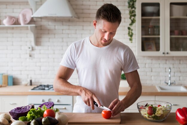 Medium shot man cutting tomato