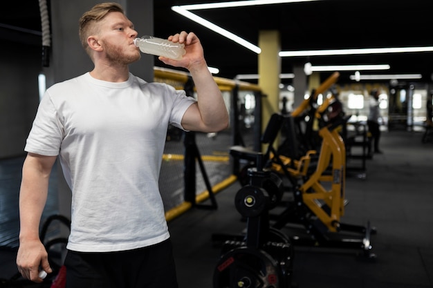 Free photo medium shot man drinking beverage at gym