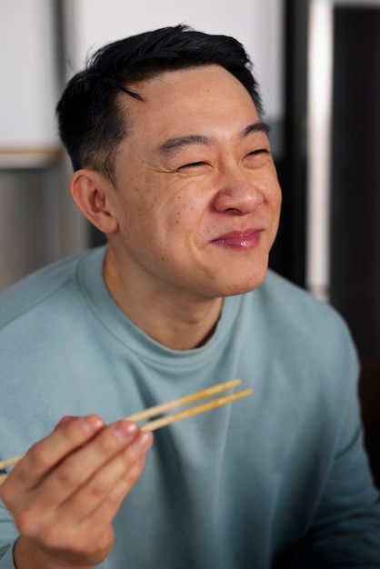 Free photo medium shot man eating asian food