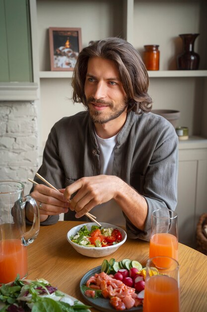 Medium shot man eating salmon bowl