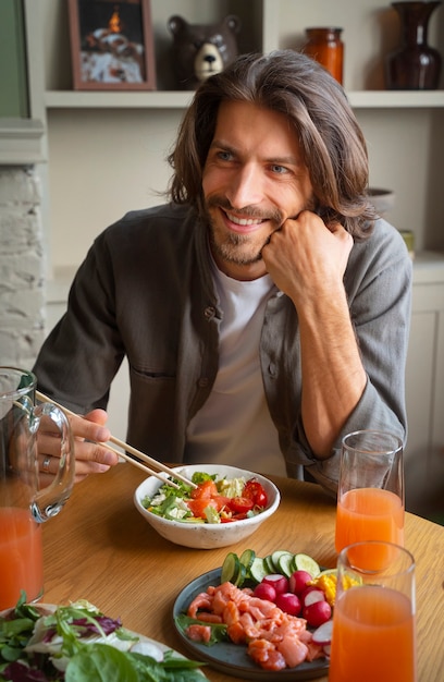 Medium shot man eating salmon bowl