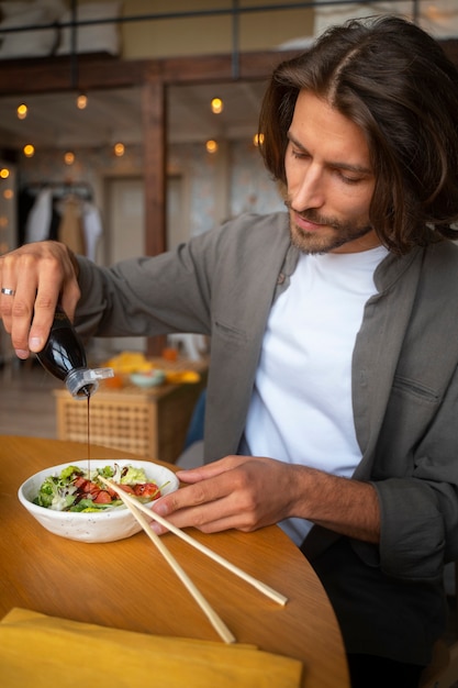 Medium shot man eating salmon bowl