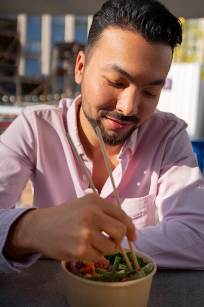 Medium shot man eating salmon bowl