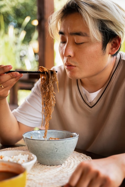 Free photo medium shot man eating with chopsticks