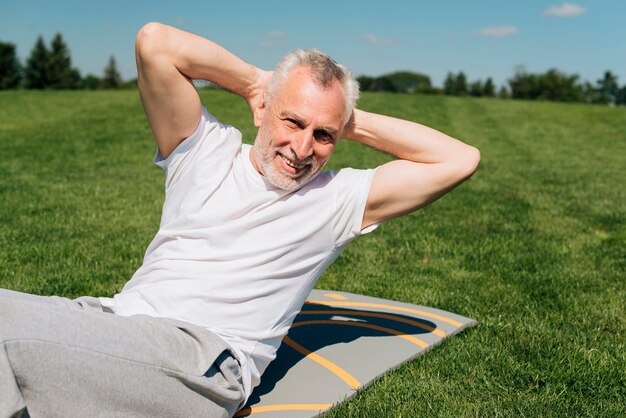 Medium shot man exercising on a mat