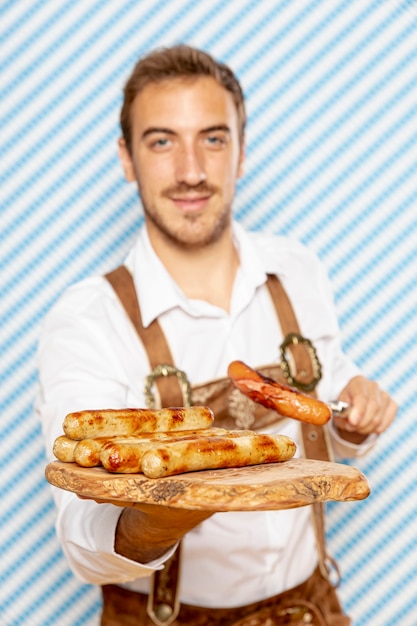 Free photo medium shot of man holding plate of german sausages