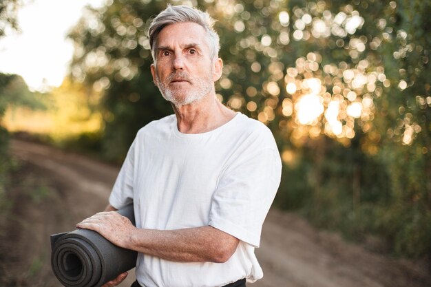 Medium shot man holding yoga mat