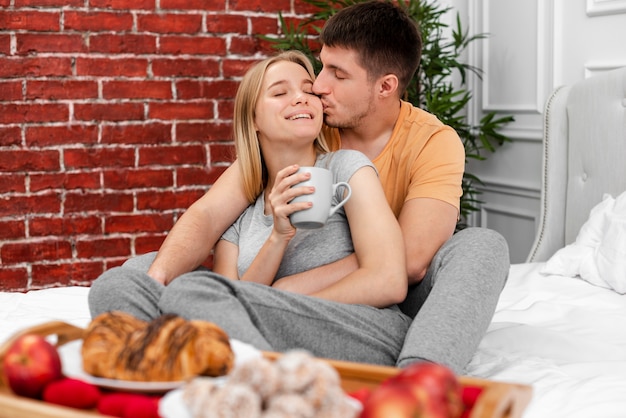 Medium shot man kissing woman with cup