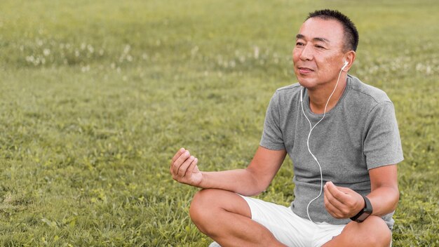 Medium shot man meditating on grass