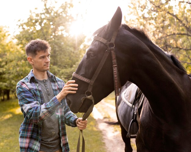 Medium shot man petting horse in nature