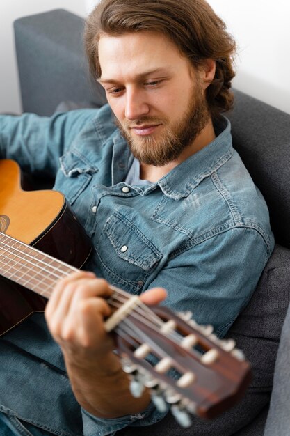 Medium shot man playing guitar at home