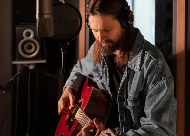 Medium shot man playing the guitar in studio