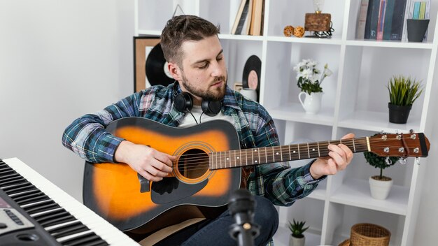 Medium shot man playing the guitar