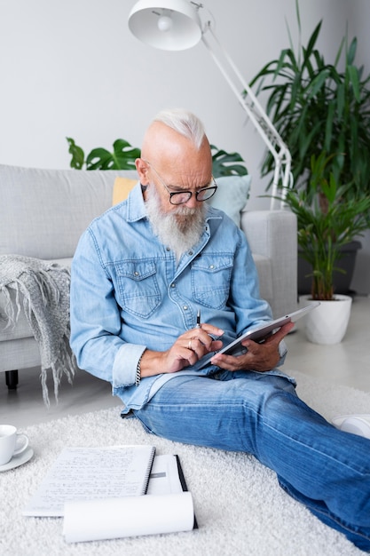 Free Photo medium shot man sitting on floor with tablet