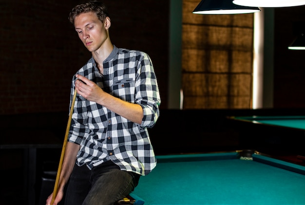 Free photo medium shot man sitting on pool table