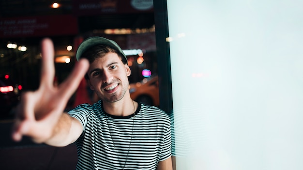 Free photo medium shot of man standing and showing peace sign