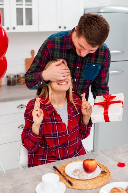 Medium shot man surprising woman with present