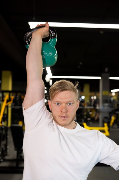 Medium shot man training with blue kettlebell