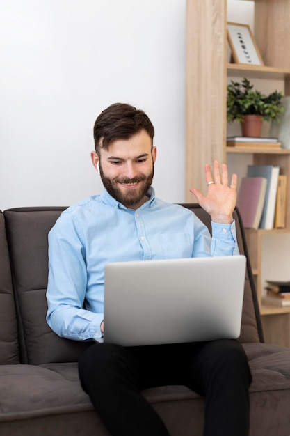 Free Photo medium shot man waving at laptop