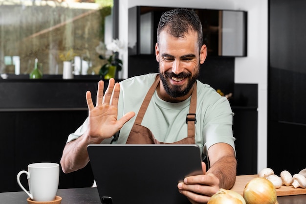 Medium shot man waving at tablet