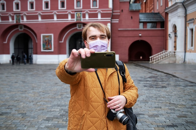 Medium shot man with face mask taking selfie