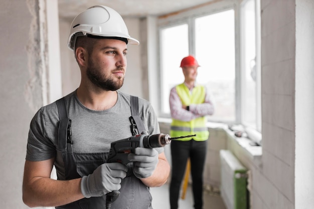 Medium shot man with helmet and drill