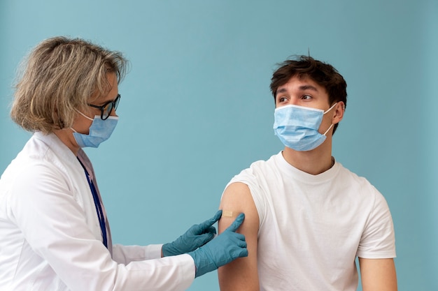 Medium shot man with mask getting vaccine