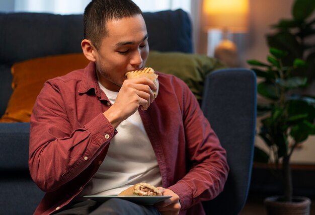 Medium shot man with  paper-wrapped sandwich