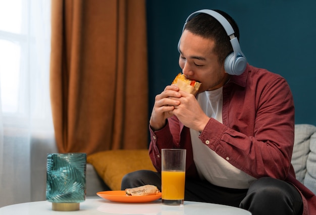 Medium shot man with  paper-wrapped sandwich