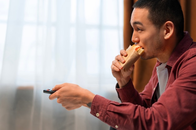 Medium shot man with  paper-wrapped sandwich